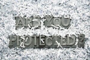 The words "are you protected" made from metallic letterpress type inside of shredded paper heap