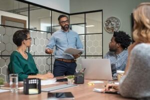 Employees listen to a presentation around a boardroom table.