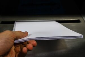 Dropping of paper in a metal bin container for safe disposal of business documents