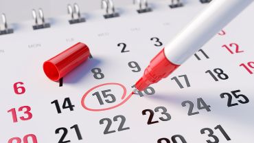 A red pen marking day of the month on a calendar for recurring scheduled shredding services.