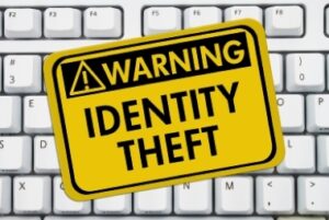 Identity Theft Warning Sign A yellow sign with the words Identity Theft on a keyboard